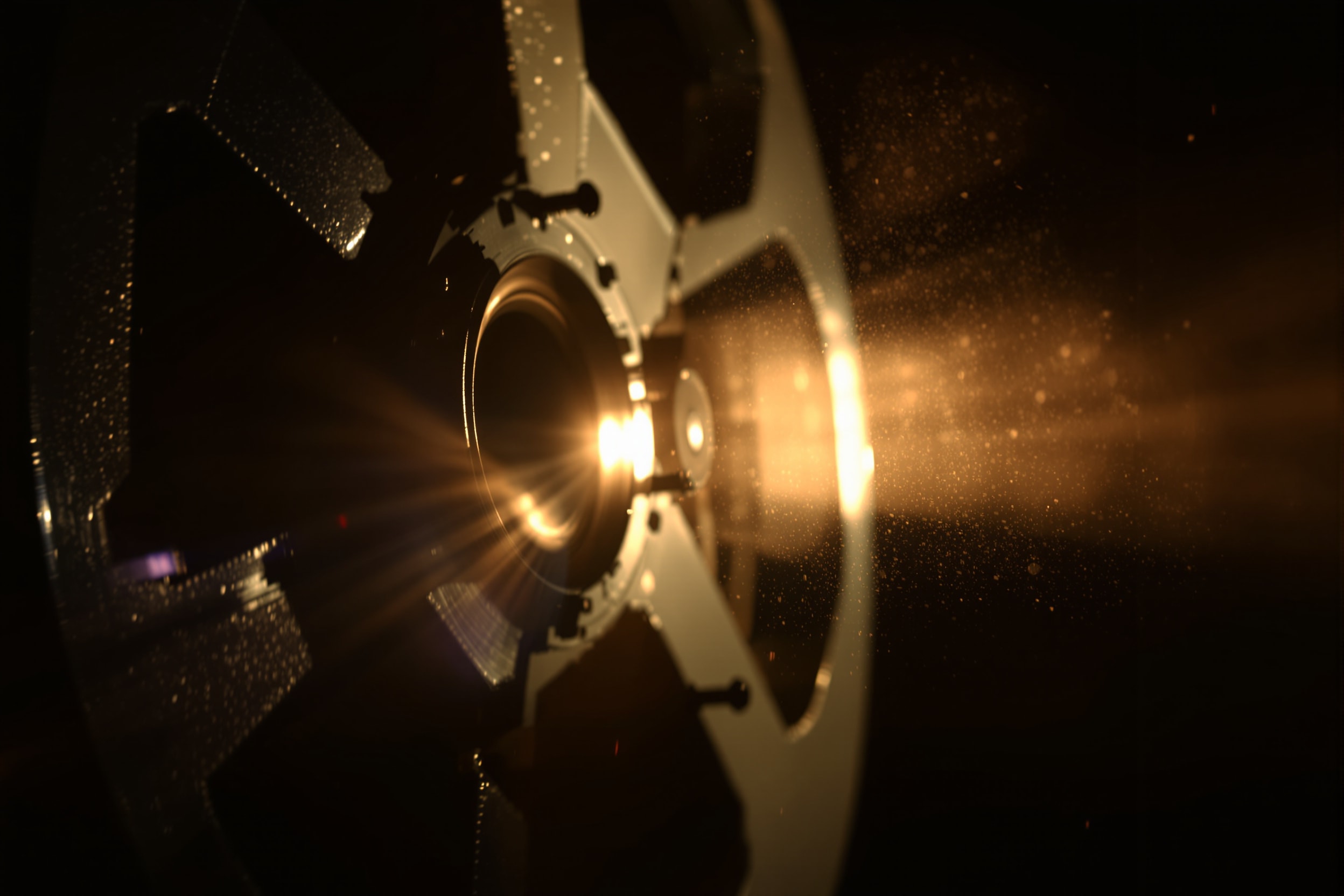 Artistic close-up of a vintage film projector lens with a warm beam of light