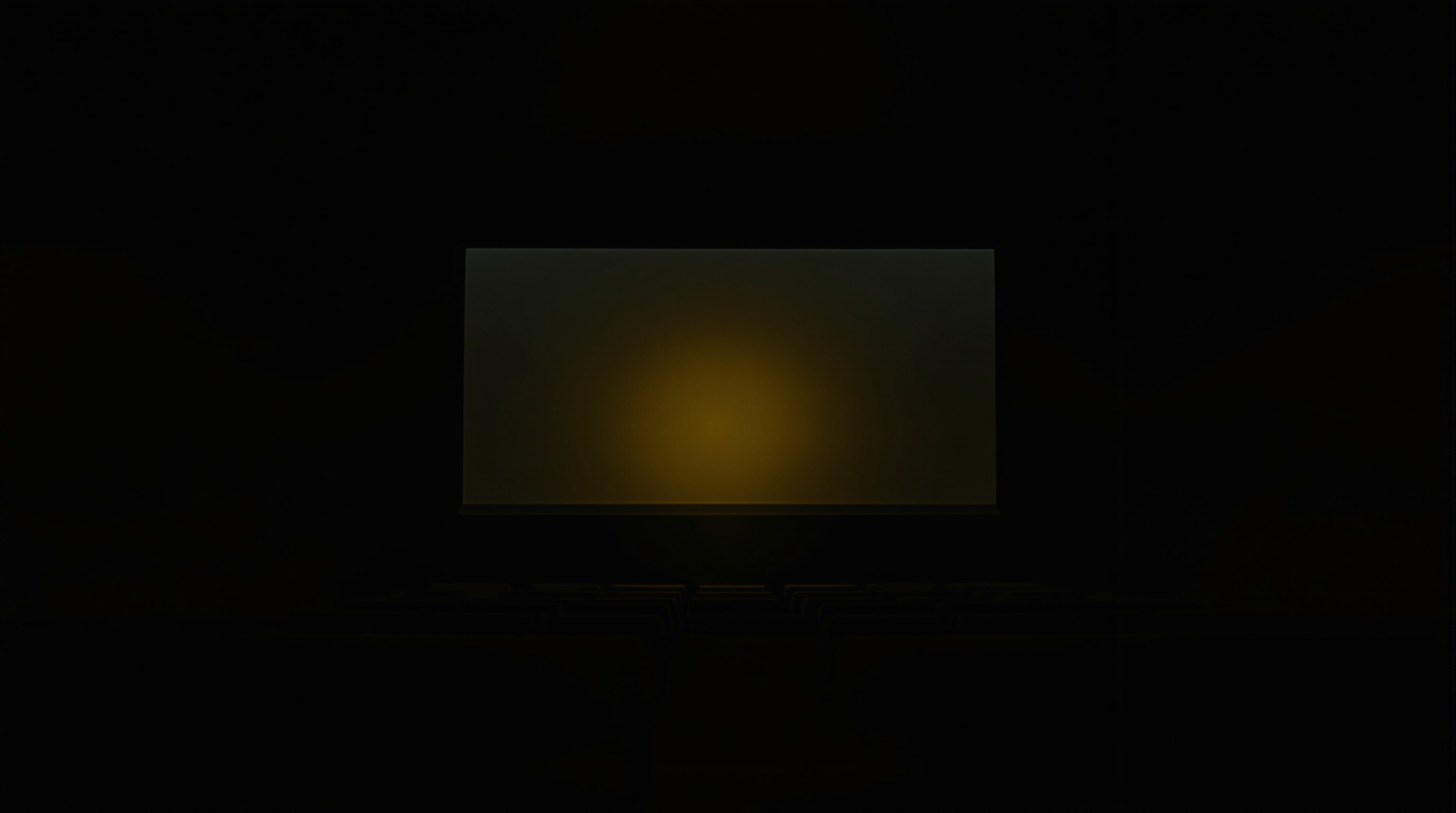 A single projector beam cutting through the darkness of an empty vintage screening room